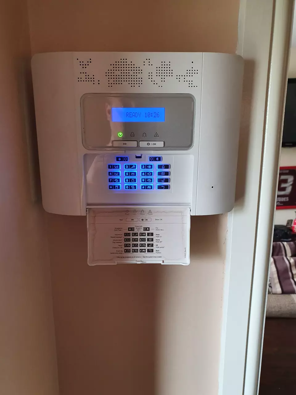 An alarm panel and keypad fitted on a hallway wall